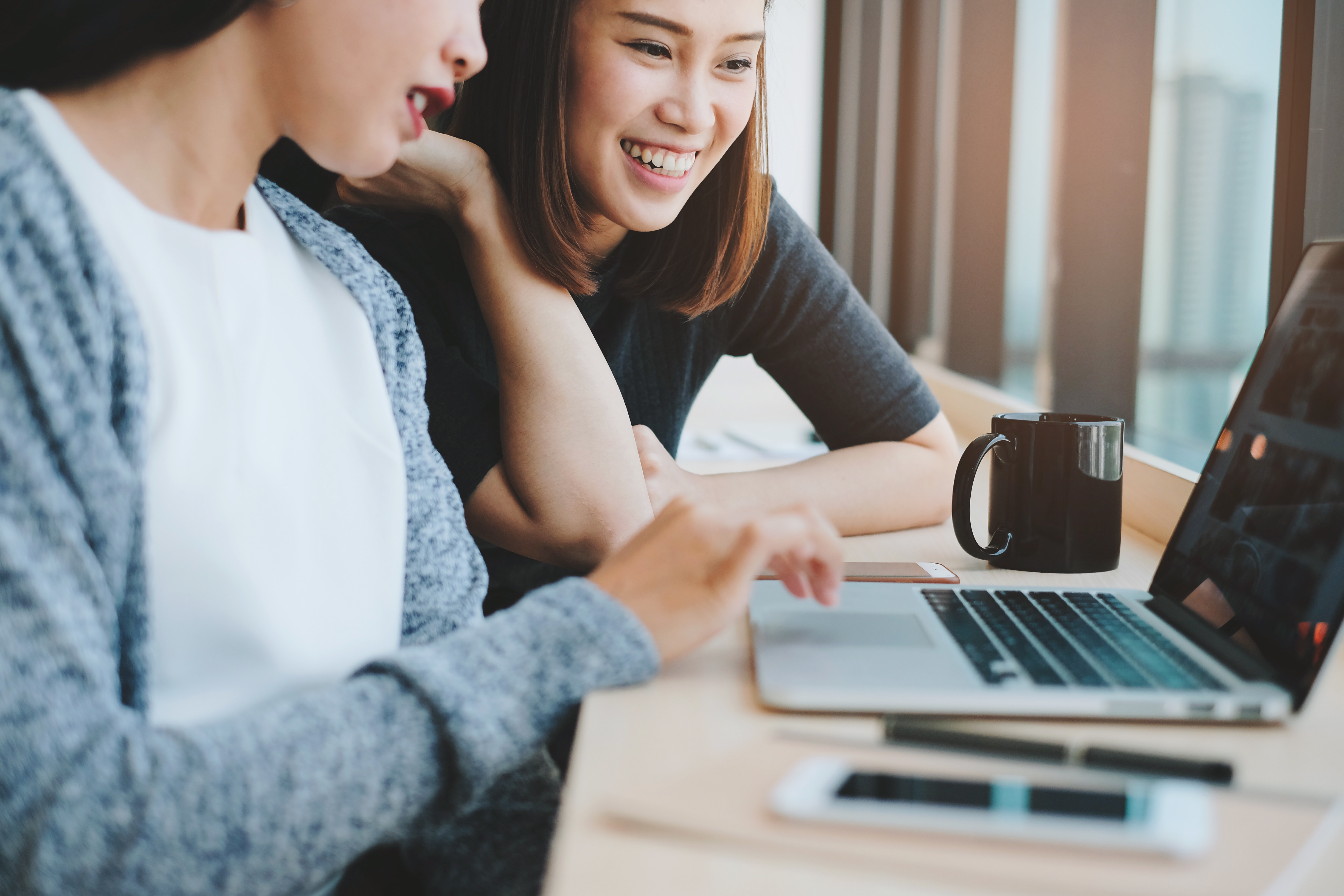 two-businesswomen-friends-smiling-and-brainstorming-while-using-laptop-in-office-or-cafe_t20_g8AZkG-1